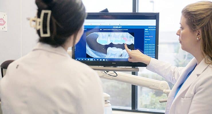 dental professionals using digital dentistry tools to examine and explain imaging results to a patient