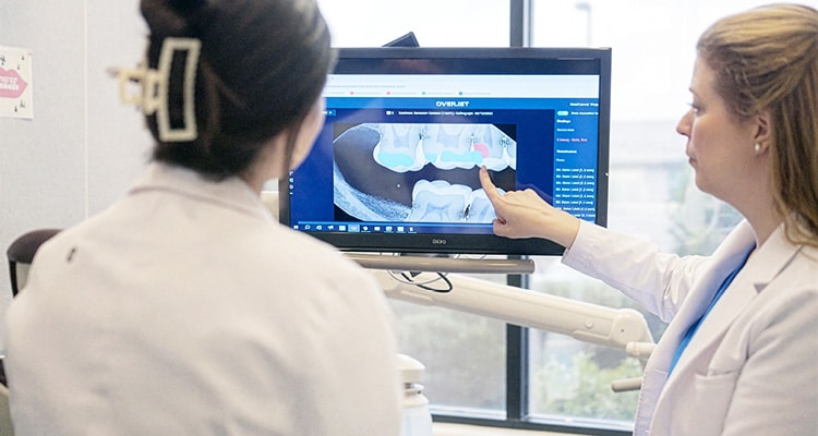 dental professionals using digital dentistry tools to examine and explain imaging results to a patient
