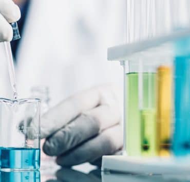 a person working in a laboratory setting, focusing on liquid measurement and chemical testing
