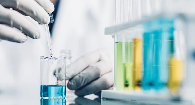 a person working in a laboratory setting, focusing on liquid measurement and chemical testing