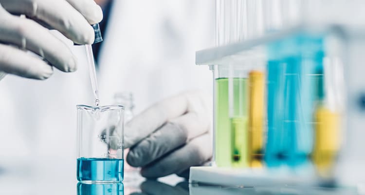 a person working in a laboratory setting, focusing on liquid measurement and chemical testing