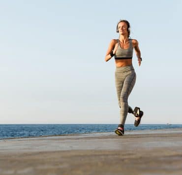 This image shows a person with a prosthetic running on a coastal path