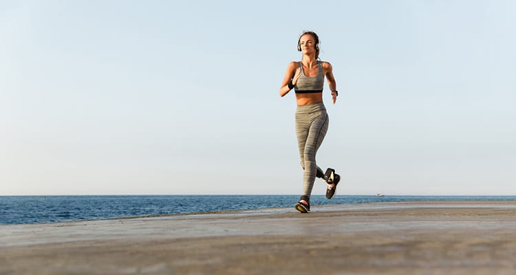 This image shows a person with a prosthetic running on a coastal path