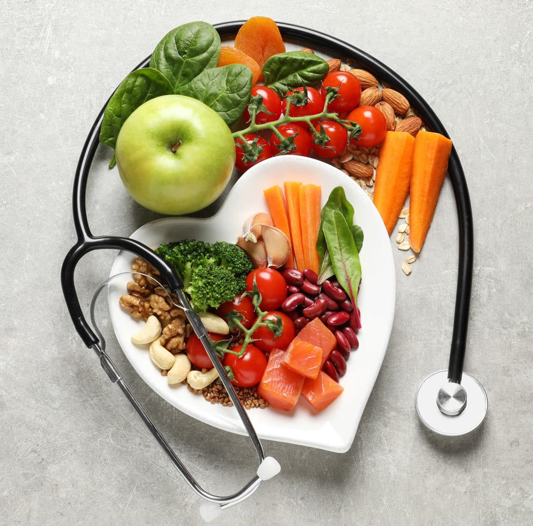 a heart-shaped plate filled with fresh, nutrient-dense foods wrapped by a stethoscope