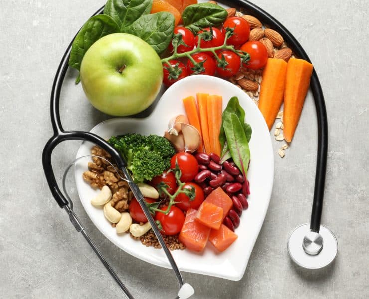 a heart-shaped plate filled with fresh, nutrient-dense foods wrapped by a stethoscope