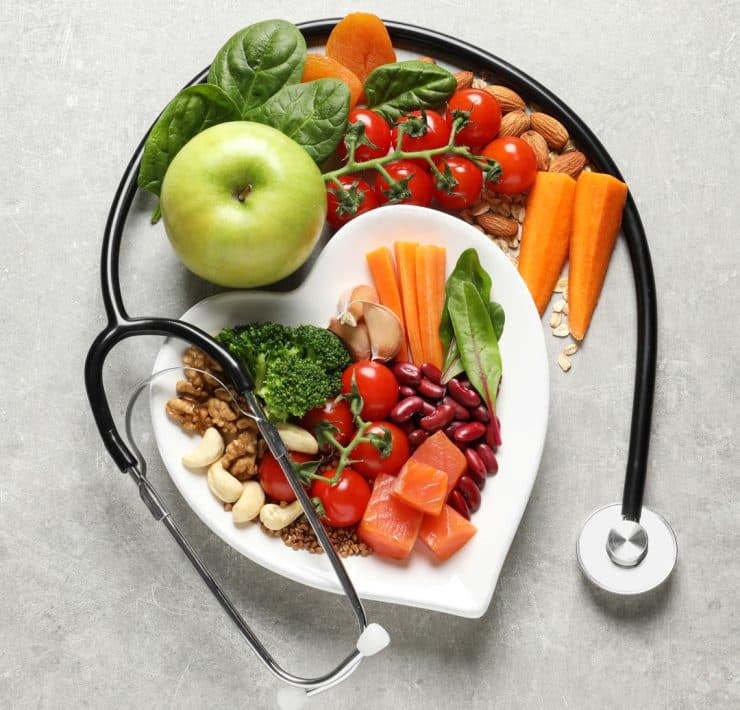 a heart-shaped plate filled with fresh, nutrient-dense foods wrapped by a stethoscope