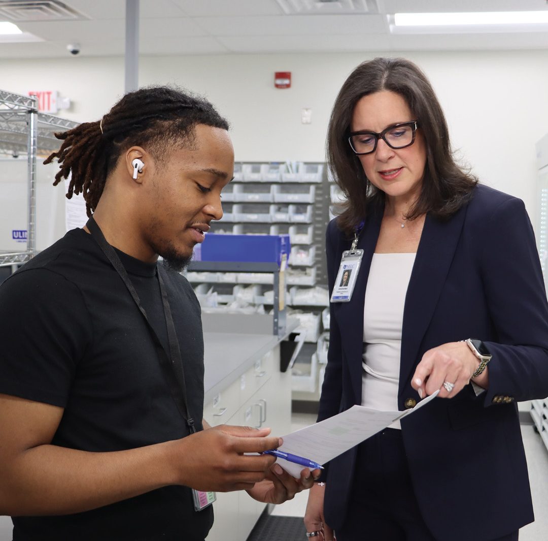 two individuals discussing papers in what appears to be a medical or clinical supply setting