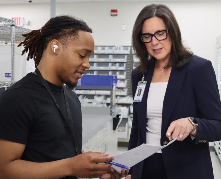 two individuals discussing papers in what appears to be a medical or clinical supply setting