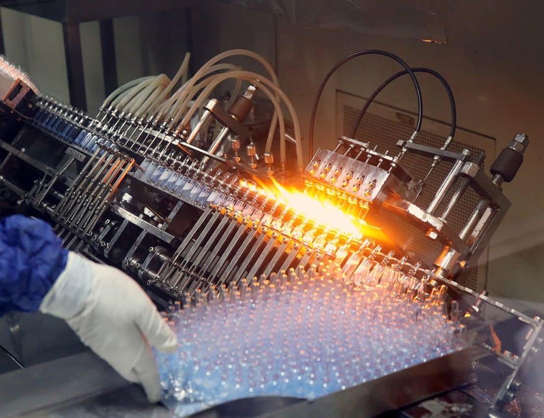 Automated pharmaceutical manufacturing equipment processing vials on a high-speed production line.