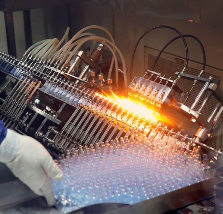 Automated pharmaceutical manufacturing equipment processing vials on a high-speed production line.