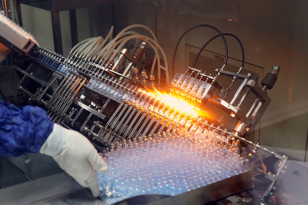 Automated pharmaceutical manufacturing equipment processing vials on a high-speed production line.