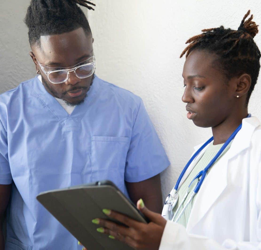 Healthcare professionals reviewing information on a tablet during clinical training.