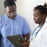 Healthcare professionals reviewing information on a tablet during clinical training.