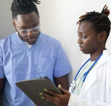 Healthcare professionals reviewing information on a tablet during clinical training.