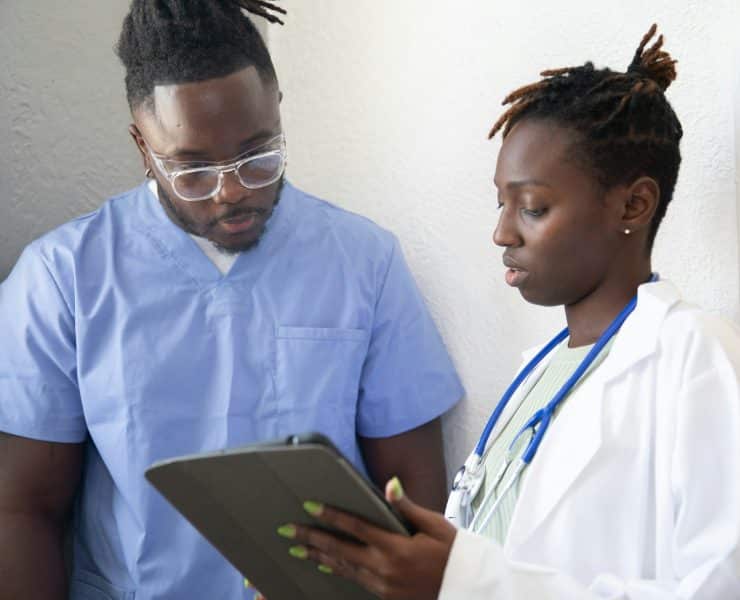 Healthcare professionals reviewing information on a tablet during clinical training.
