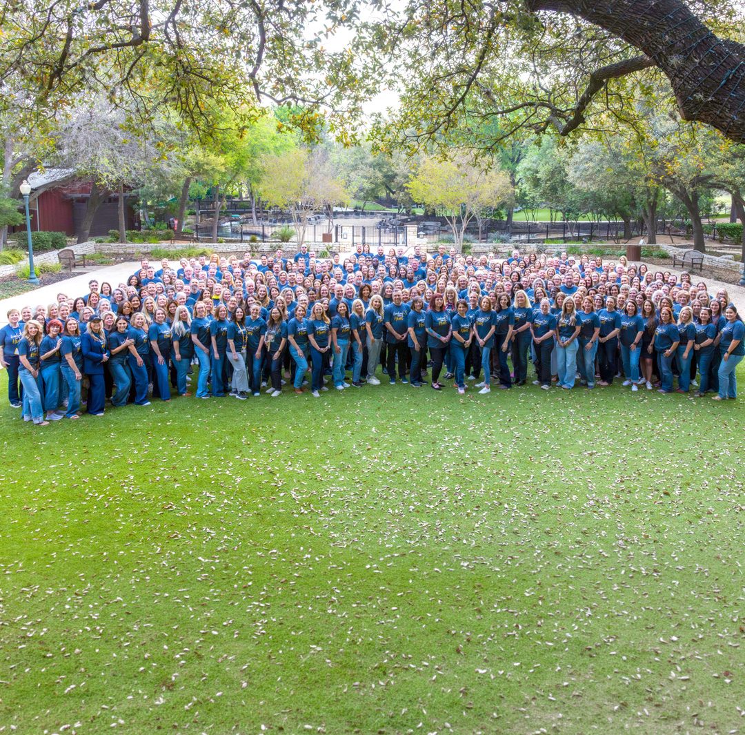 a large group photo of employees and leaders from Compassus gathered on the lawn during a company event