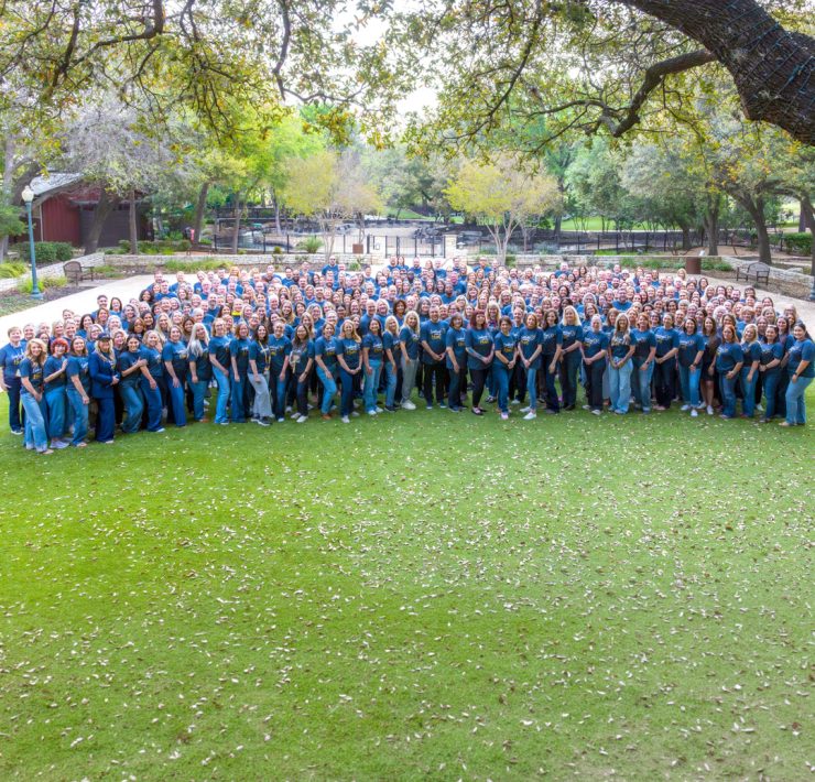 a large group photo of employees and leaders from Compassus gathered on the lawn during a company event
