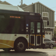 Yellow and white city bus travelling along a residential street.