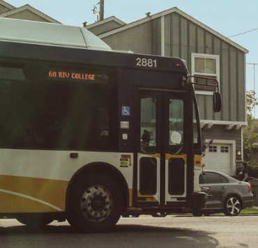 Yellow and white city bus travelling along a residential street.