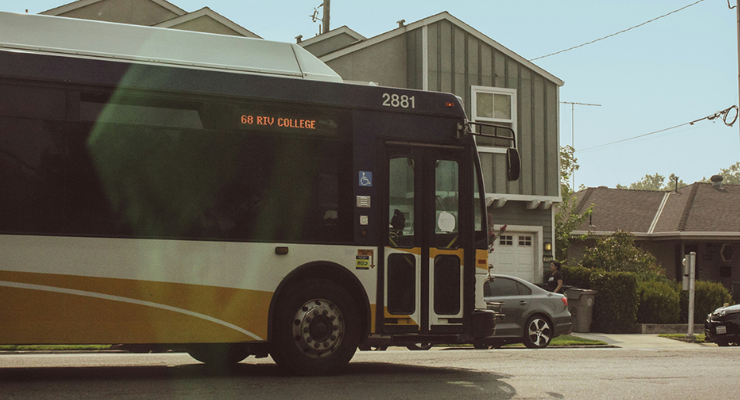 Yellow and white city bus travelling along a residential street.