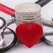 Stethoscope, red heart and stack of coins representing healthcare costs and funding.