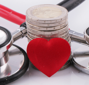 Stethoscope, red heart and stack of coins representing healthcare costs and funding.