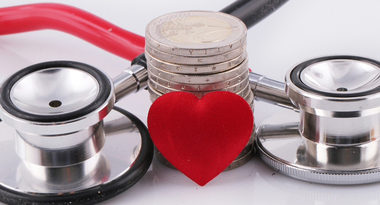 Stethoscope, red heart and stack of coins representing healthcare costs and funding.