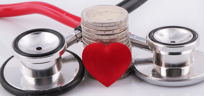 Stethoscope, red heart and stack of coins representing healthcare costs and funding.